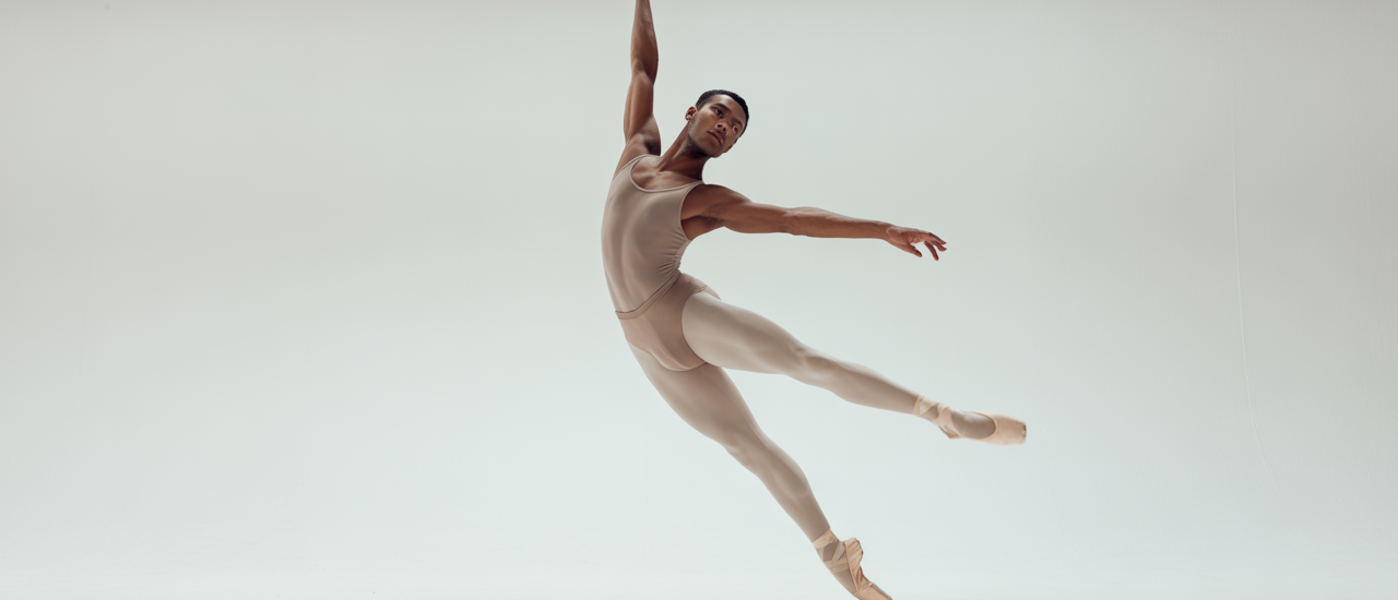 Adult ballet dancer performing an elegant ballet pose in a professional studio with white background