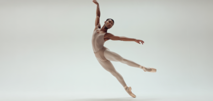 Adult ballet dancer performing an elegant ballet pose in a professional studio with white background