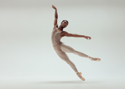 Adult ballet dancer performing an elegant ballet pose in a professional studio with white background