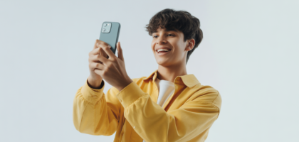 Photorealistic image of a young content creator filming TikTok video with smartphone on white background